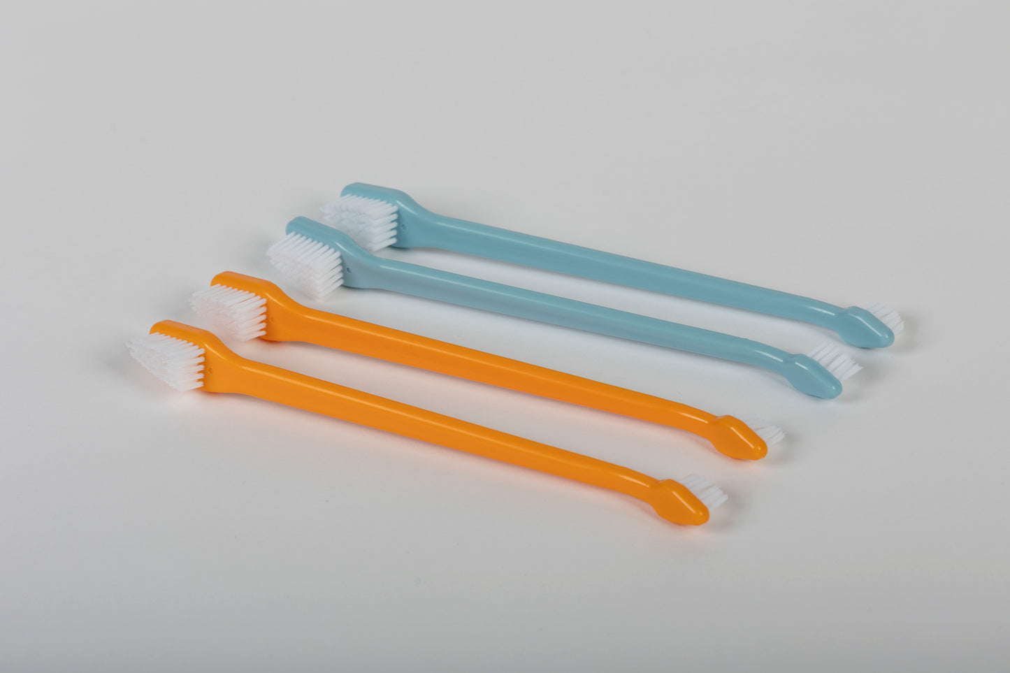 Two orange and two light blue professional pet toothbrushes on a white background.