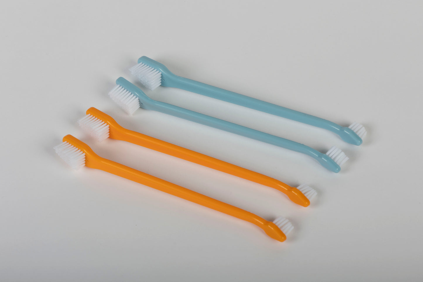 Two orange and two light blue professional pet toothbrushes on a white background